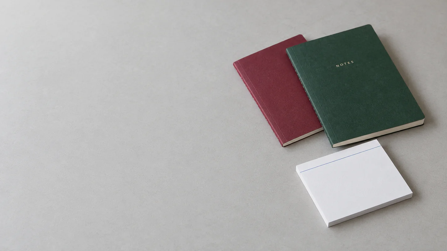 Paper-cover notebooks and a writing pad on a clean gray tabletop